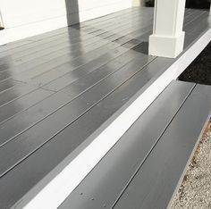 a close up of a wooden porch with white posts and gray wood planks on it