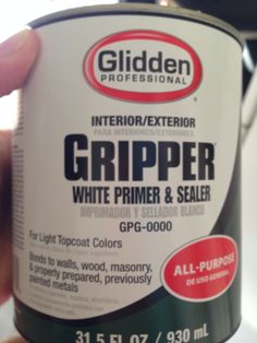 a person holding a can of white primer and sealer in their left hand