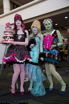 three women dressed up in costumes standing next to each other with cake on their hands