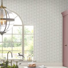 a kitchen with pink cabinets and wallpaper in the background is an arched window that looks out onto a garden