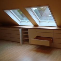 an empty room with two skylights on the roof and drawers in the wall below