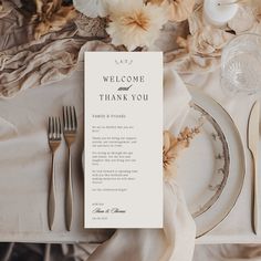 a table set with silverware, flowers and a welcome card on top of it