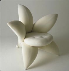 a white chair sitting on top of a white floor next to a plant shaped object