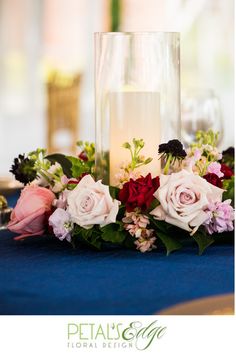 a candle and flowers on a blue table cloth at a wedding reception with the bride's name written on it