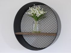 a vase filled with white flowers sitting on top of a shelf next to a wall