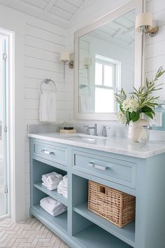 a bathroom with blue cabinets and white towels on the counter top, along with a large mirror over the sink