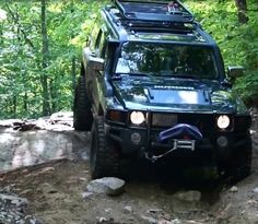 a black jeep driving down a dirt road in the woods