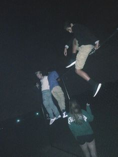 three skateboarders doing tricks in the dark