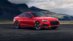 a red car parked in front of some mountains