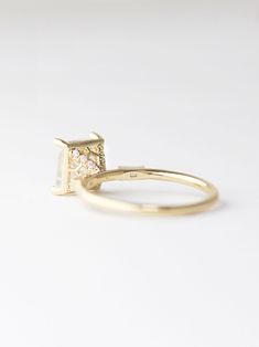 a yellow gold ring with two diamonds on the front and side, sitting on a white surface