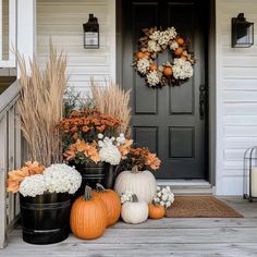 fall front porch decor with pumpkins, mums and flowers in black buckets