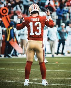 a football player is giving the thumbs up sign on the sidelines during a game