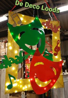 a green and red sign hanging from the side of a building with lights on it