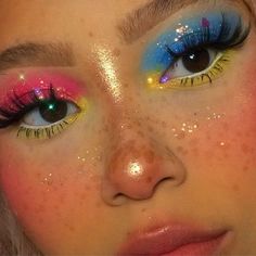 a close up of a woman's face with bright makeup and colorful eyeliners