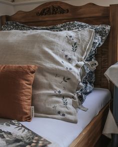 a bed topped with lots of pillows next to a window