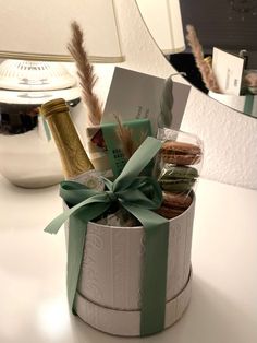 an open gift box filled with cookies and wine bottles on a table next to a mirror