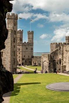 people are walking around in front of an old castle