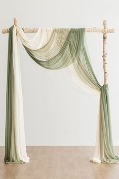 a white and green drape with bamboo sticks on the floor in front of a wall