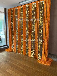 an orange and black backdrop with gold flowers on it in front of a large window