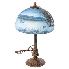 a lamp that is sitting on top of a table with a painting on the shade