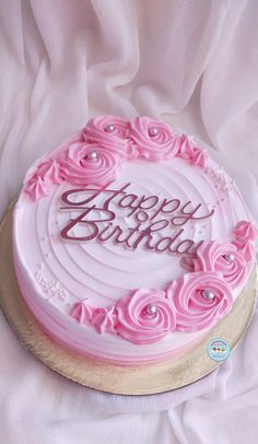 a birthday cake with pink frosting and roses on it's side that says happy birthday