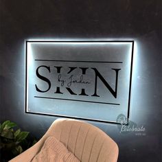 an illuminated sign above a chair in front of a wall with the word skin on it