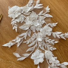 a piece of white lace with flowers and leaves on it next to a pair of scissors