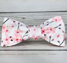 "Pale pink cherry blossoms on white cotton sateen. Because of the handmade nature of these bowties they can vary in size ever so slightly but on average the bow measures 5 inches by 2 inches when tied. hand wash/ spot wash only The self-tied option will be made in the style pictured. The pre-tied option will have the addition of a hook in the back, and the bow will be stitched in the tied position. RETURNS: I accept returns on items in original, unused condition. You will receive a refund for th White Summer Bow For Gifts, Spring Wedding Bow, Pink Bow Gift For Spring, Elegant White Bow Tie For Spring, Pink Butterfly Knot Bow For Summer, Elegant Bow Tie For Spring Gifts, White Satin Bow Tie For Spring, Decorative Bow For Spring Gifts, Spring Butterfly Knot Bow Gift