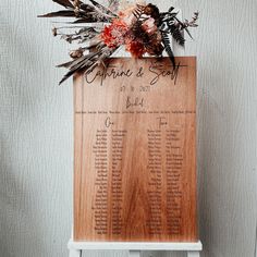 a wooden sign with flowers and feathers on it