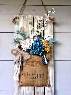 a wooden sign hanging on the side of a building with flowers and books in it