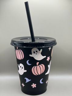 a cup with a straw in it that has halloween decorations and ghostes on it