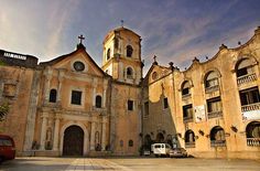 an old church with two cars parked in front of it and another building behind it