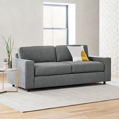 a living room with a gray couch and white rug