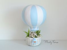 a blue and white striped hot air balloon in a basket with succulents