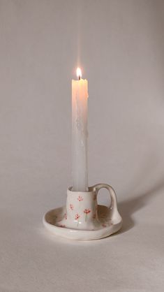 a lit candle in a teacup on a saucer