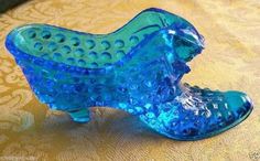 a blue glass shoe sitting on top of a table