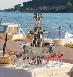 a table topped with lots of wine glasses next to a large silver bowl filled with food