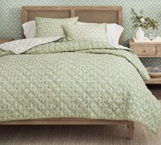 a bed with green and white bedspread in a bedroom next to two nightstands