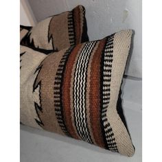 two brown and black striped pillows sitting on top of a white floor next to a wall