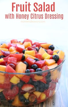 fruit salad with honey citrus dressing in a glass bowl on top of a wooden table