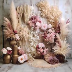 an arrangement of flowers and feathers in front of a wall with other items on it