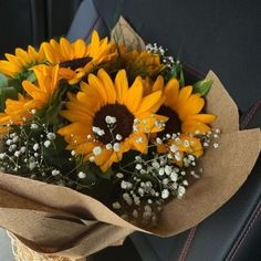 a bouquet of sunflowers sitting in the back seat of a car with baby's breath