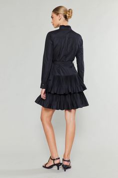 Get ready for a statement piece with this all-black, high-neck shirt dress. Carefully crafted pleats add texture and structure, highlighting the neckline and placket, as well as the skirt's tiers. Elegant Daywear Mini Dress With Tiered Skirt, Elegant Mini Dress With Tiered Skirt For Daywear, Elegant Tiered Skirt Mini Dress For Daywear, Fitted Pleated Tiered Mini Dress, Fitted Dress With Pleated Waist And Tiered Skirt, Chic Pleated Tiered Skirt Dress, Black Pleated Tiered Dress, Fitted Dress With Pleated Hem And Tiered Skirt, Party Dress With Pleated Waist And Tiered Skirt