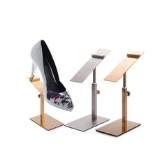 three different types of high heels and desks on metal stands, each with an individual's shoe in the middle