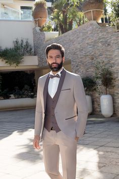 a man in a suit and bow tie is standing on the sidewalk with his hands in his pockets