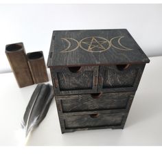 a wooden box with three drawers and two pen holders next to it on a white surface