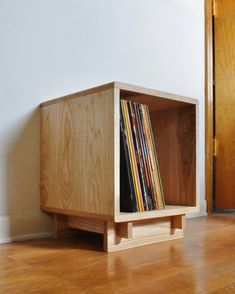 a wooden shelf with various records in it on the floor next to an open door