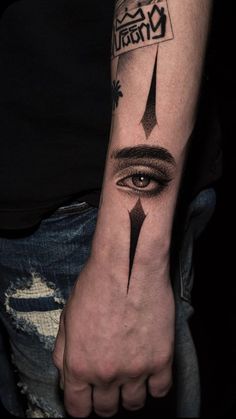 a man's arm with an eye and arrow tattoo on the left side of his arm