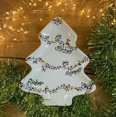 a white ceramic christmas tree ornament on top of a wooden table with lights