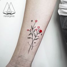 a small flower tattoo on the left inner forearm and wristband, with red flowers growing out of it